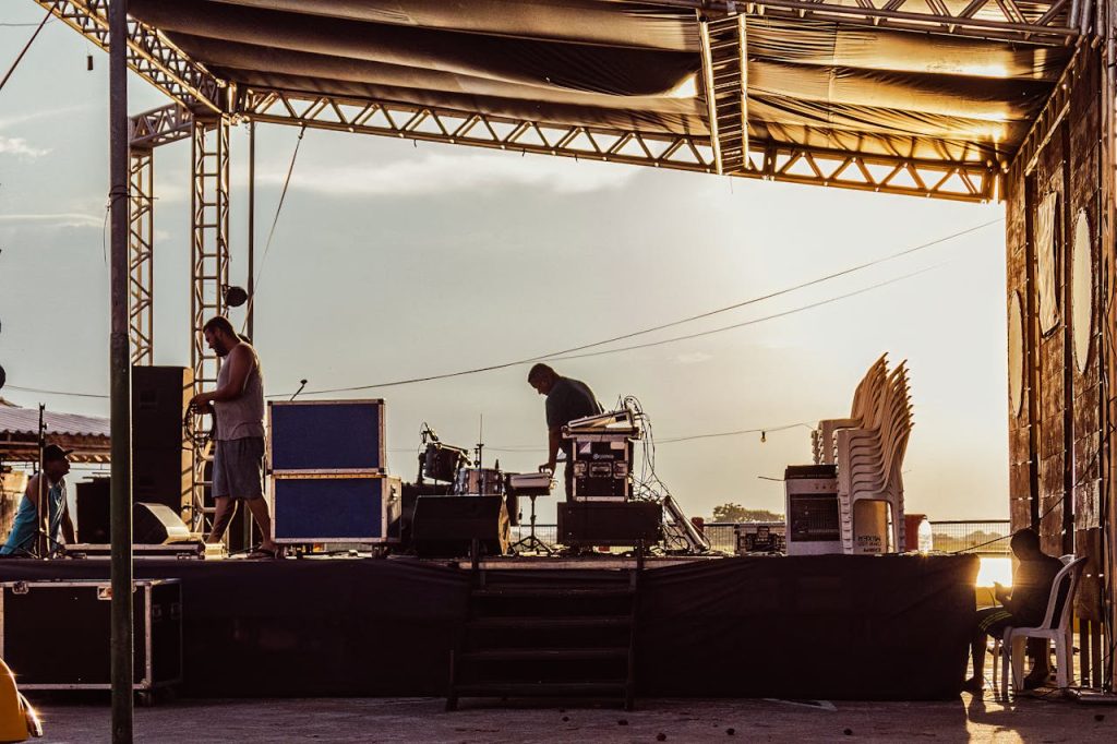 pexels photo 16085578 Musicians preparing outdoor stage during sunset with equipment and instruments.